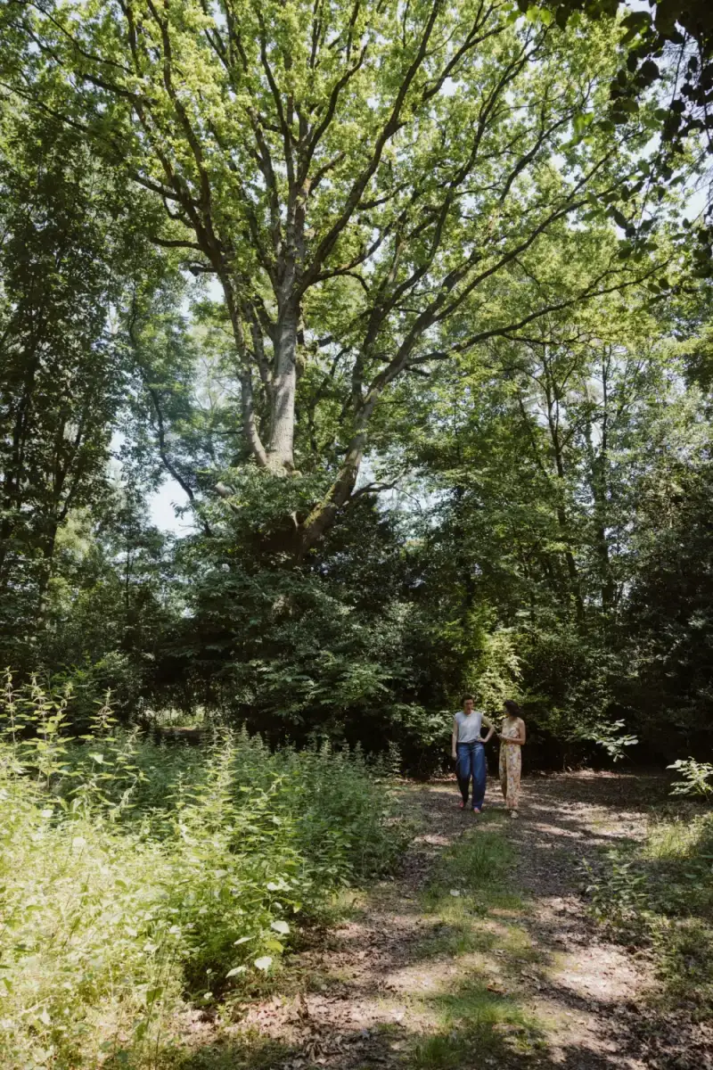Twee mensen wandelen onder de bomen rond De Kluizerij in Affligem